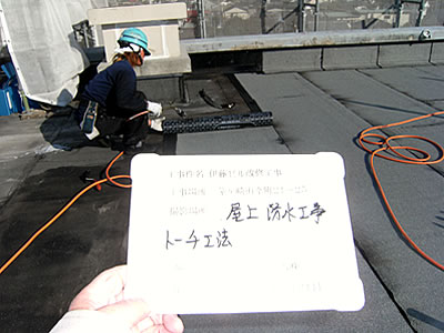 施工中状況（屋上アスファルト防水敷設作業）